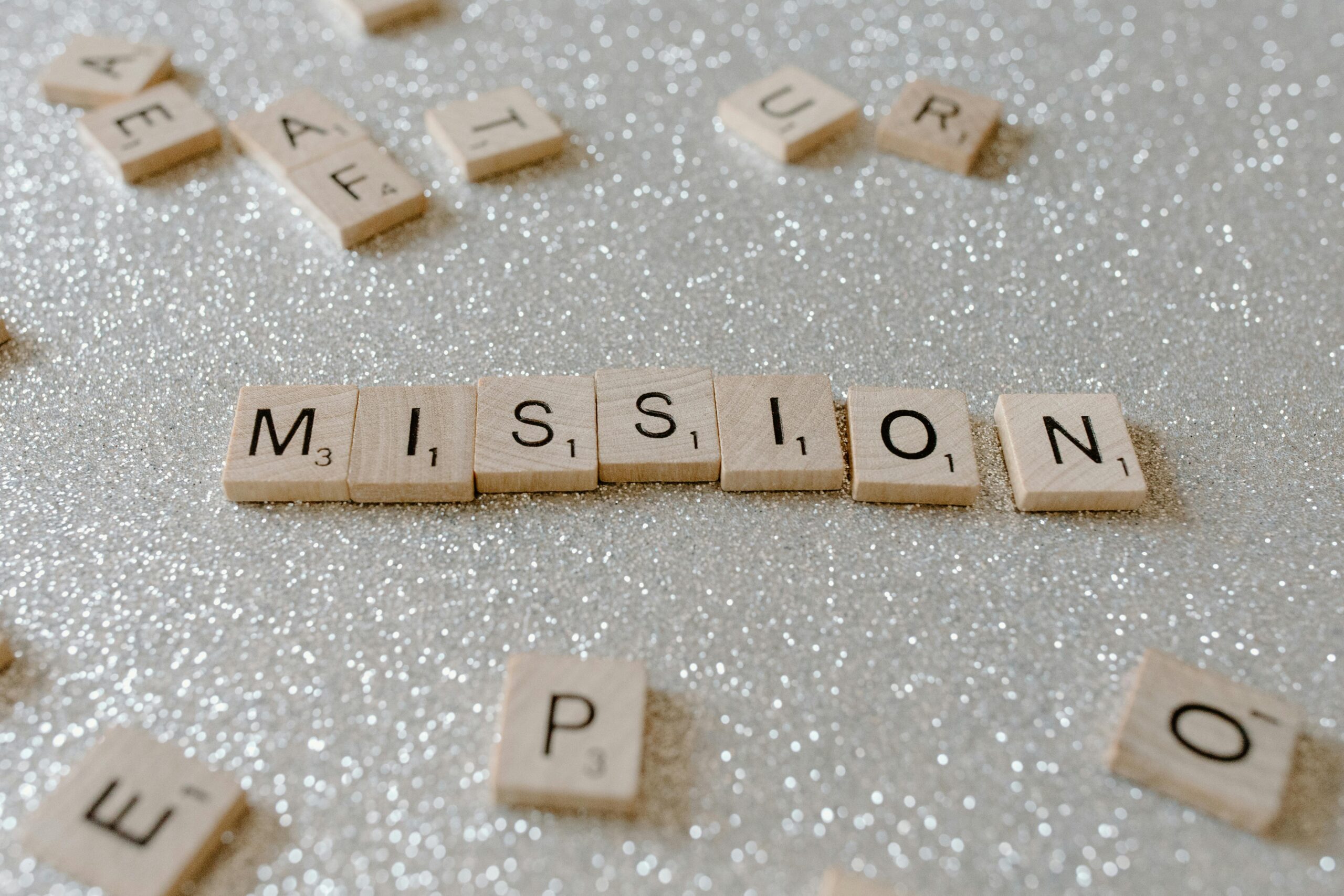 About Scrabble tiles spelling 'Mission' on a sparkling surface convey determination and goals.