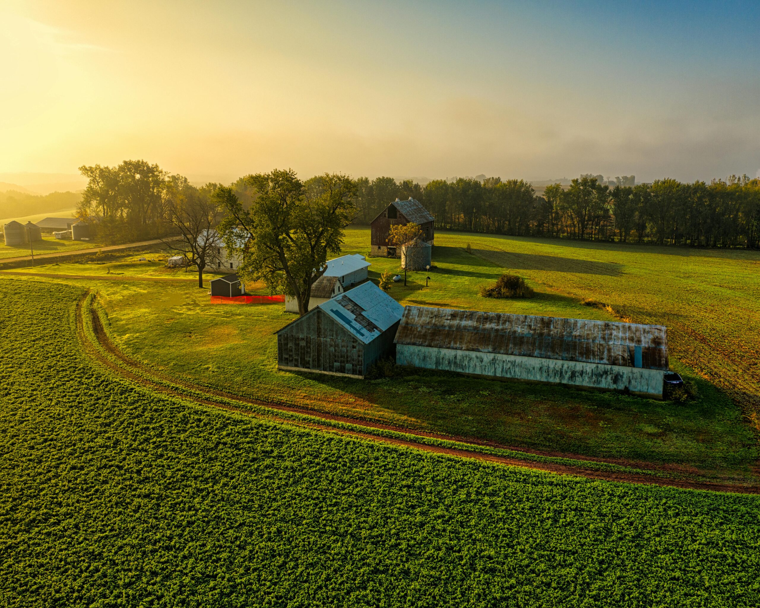 Stunning aerial photo of a rural farm in Minnesota, showcasing lush fields and historic barns at sunrise.