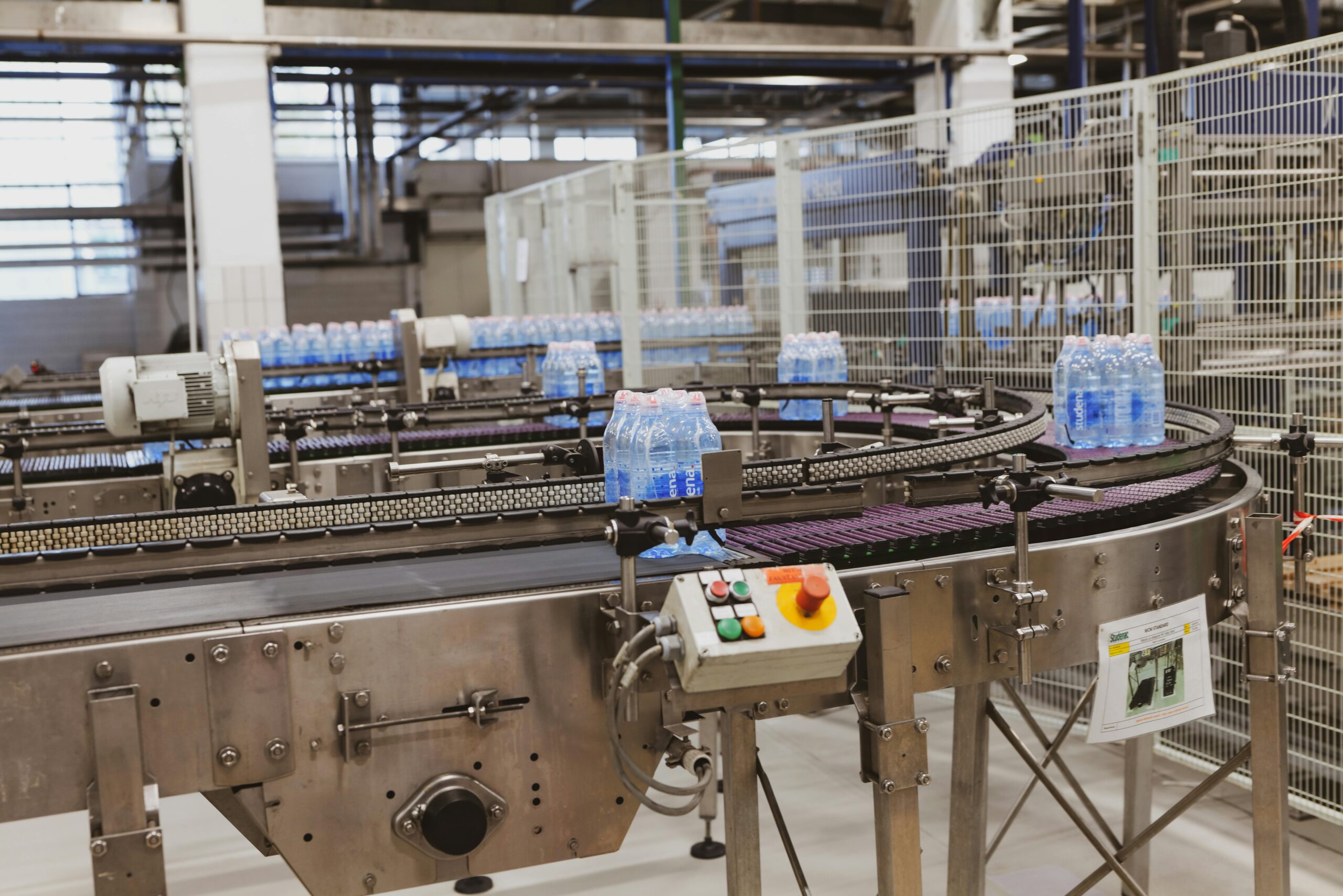 Water bottles being processed on an automated conveyor in a modern factory setting.