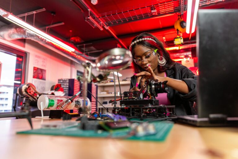 Skilled female technician working on electronic repairs in a brightly lit workshop.